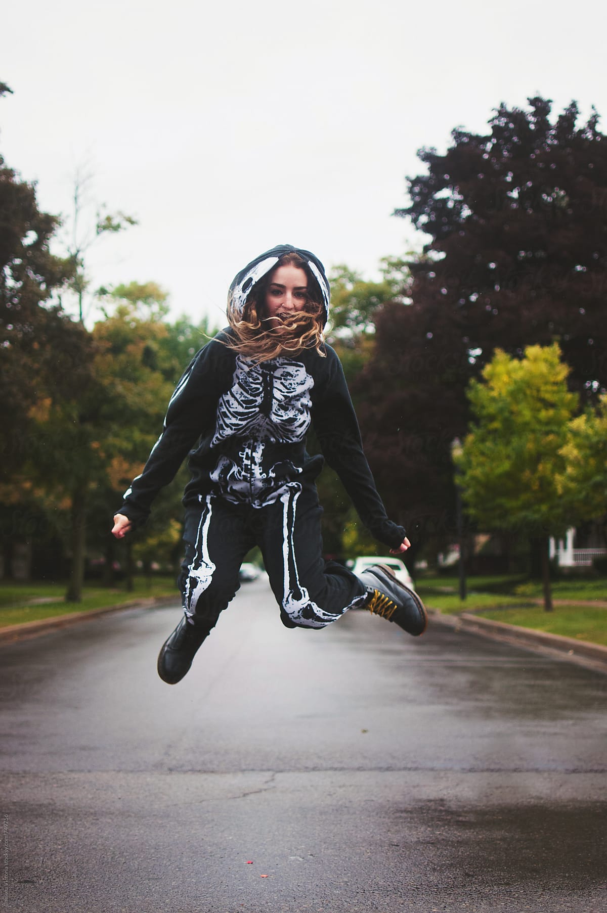 A young woman wearing a skeleton onesie jumping in the air