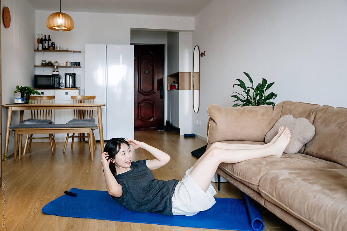 Young woman doing situps in living room