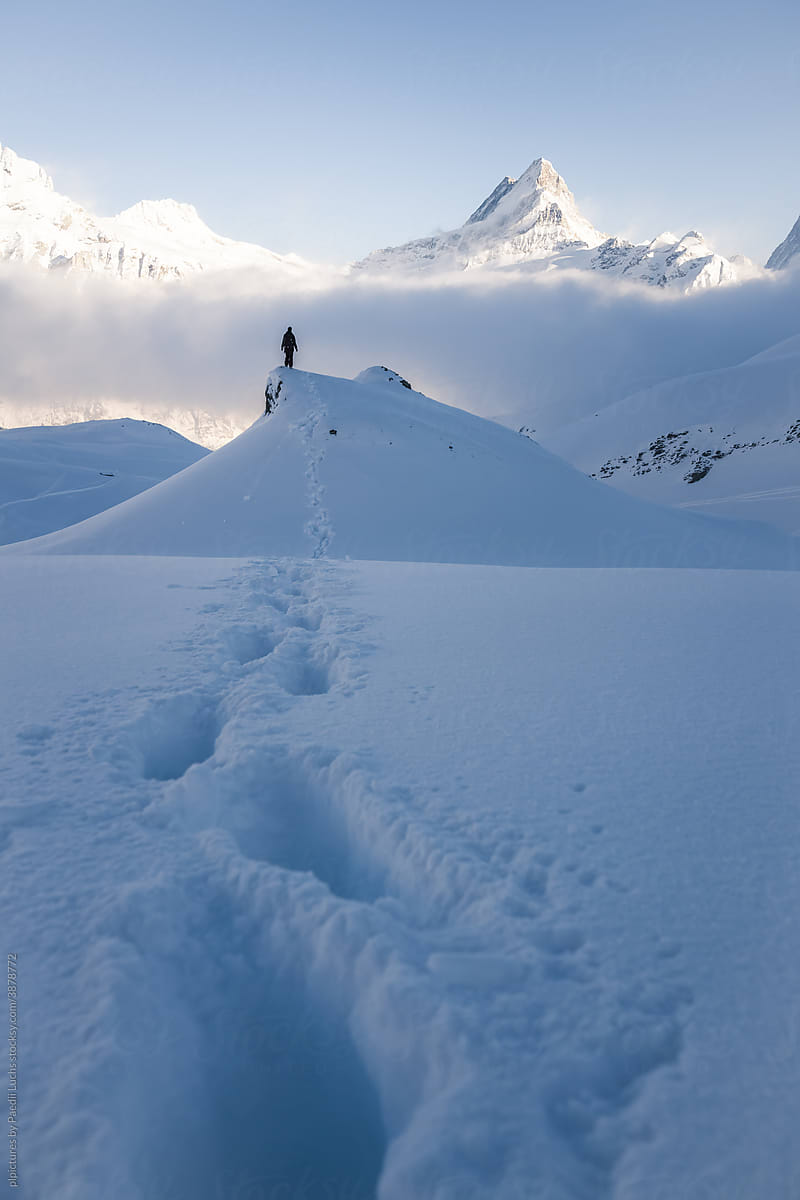 Tracks in snow & person standing in front of mountains
