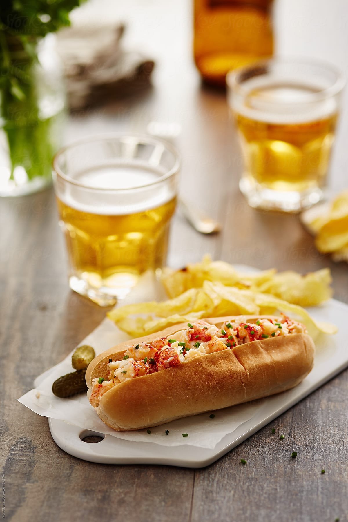 Close-up of lobster roll with pickles and cold beer