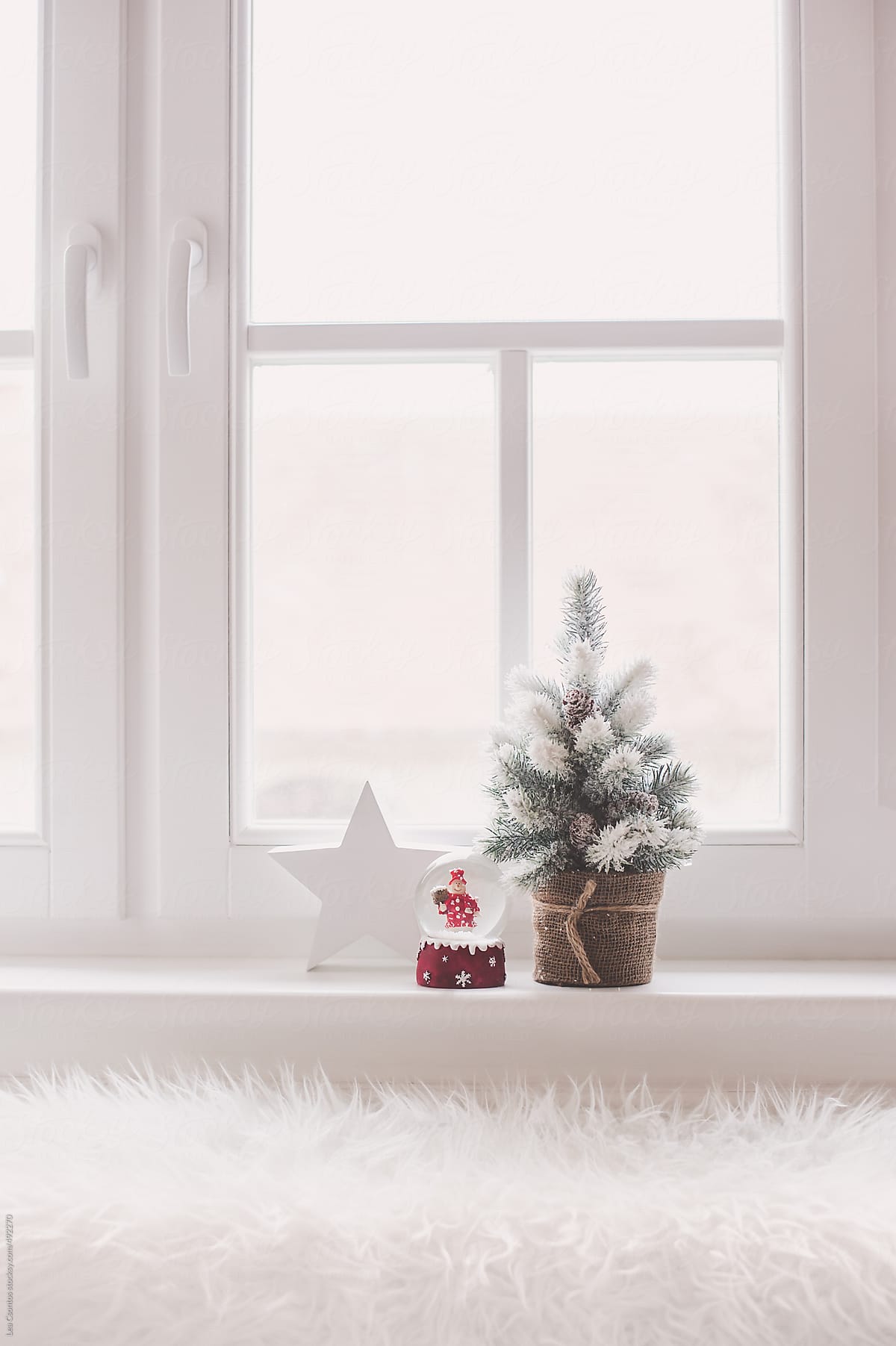 Small snow covered christmas tree with a snow globe and a wooden star