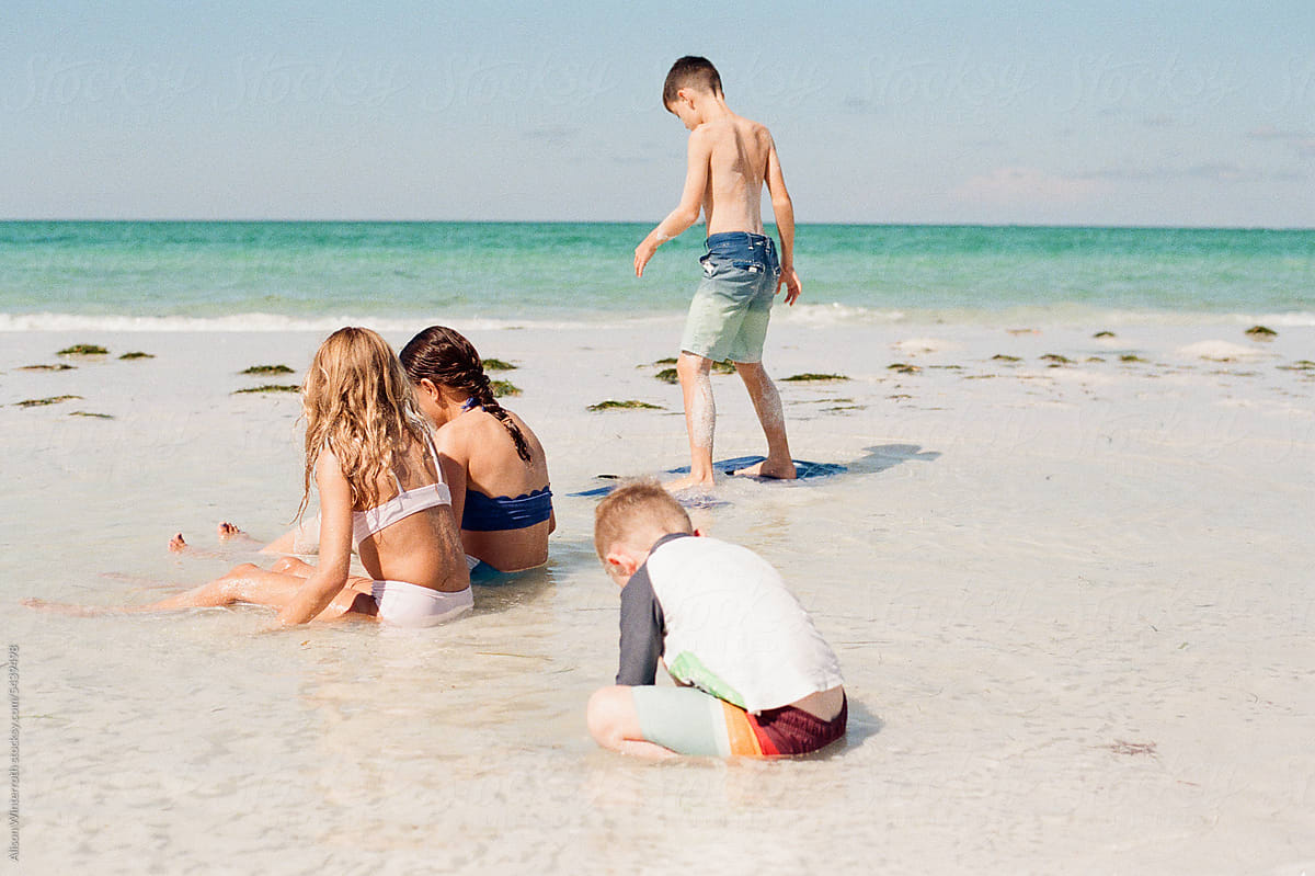 Four kids playing in shallow water at the beach