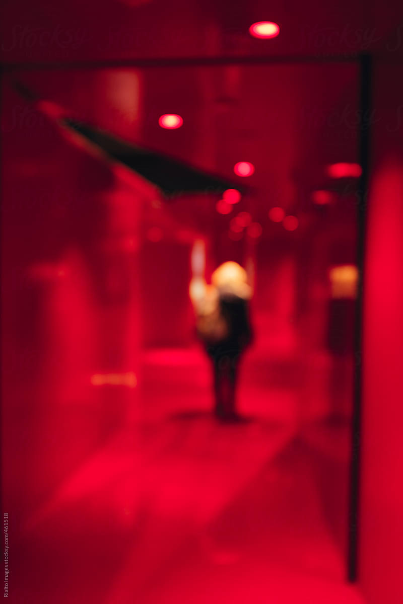 Woman walking down red hallway, blurred focus