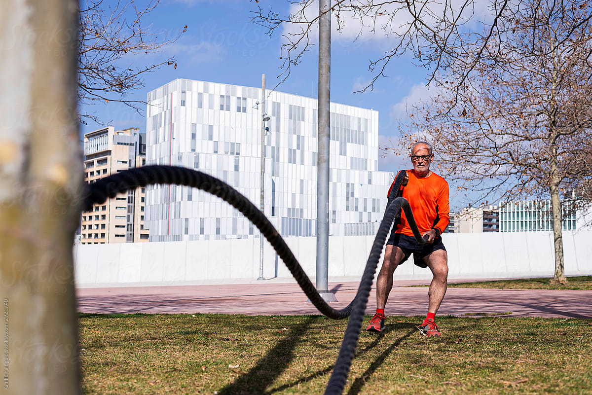 Senior man exercising with ropes in park