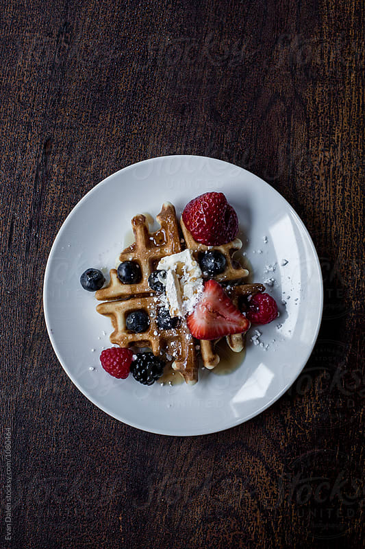 A Waffle Dish With Berries And Syrup
