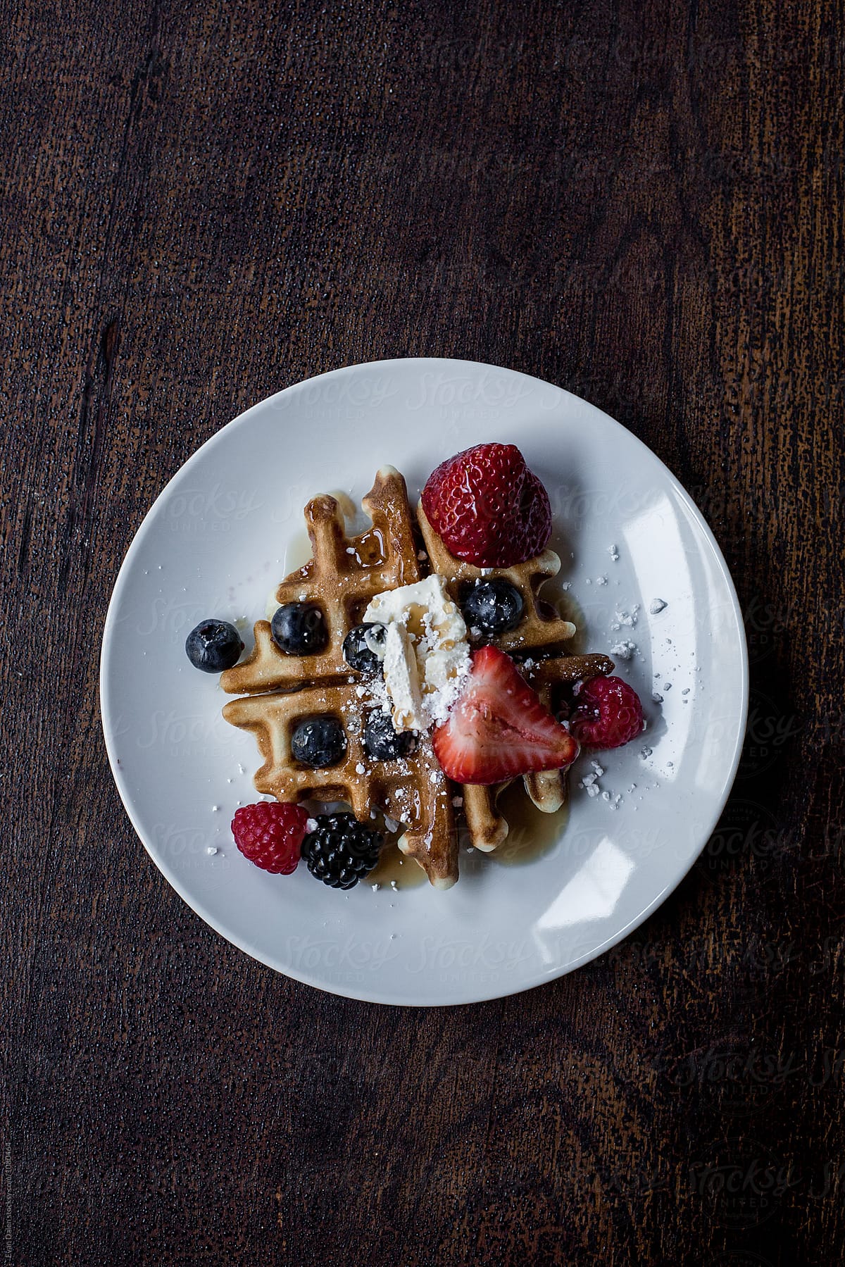 A Waffle Dish With Berries And Syrup