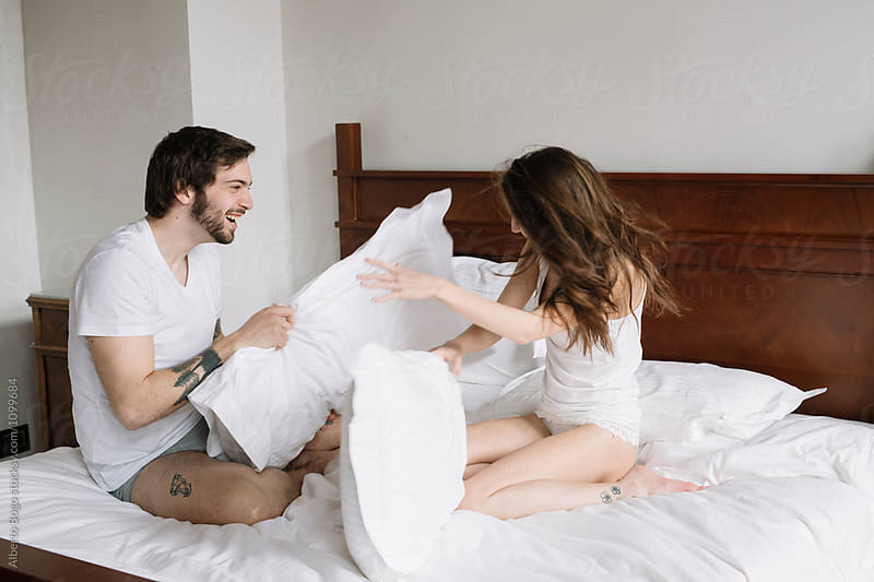 Boyfriend and girlfriend playing with pillows on bed
