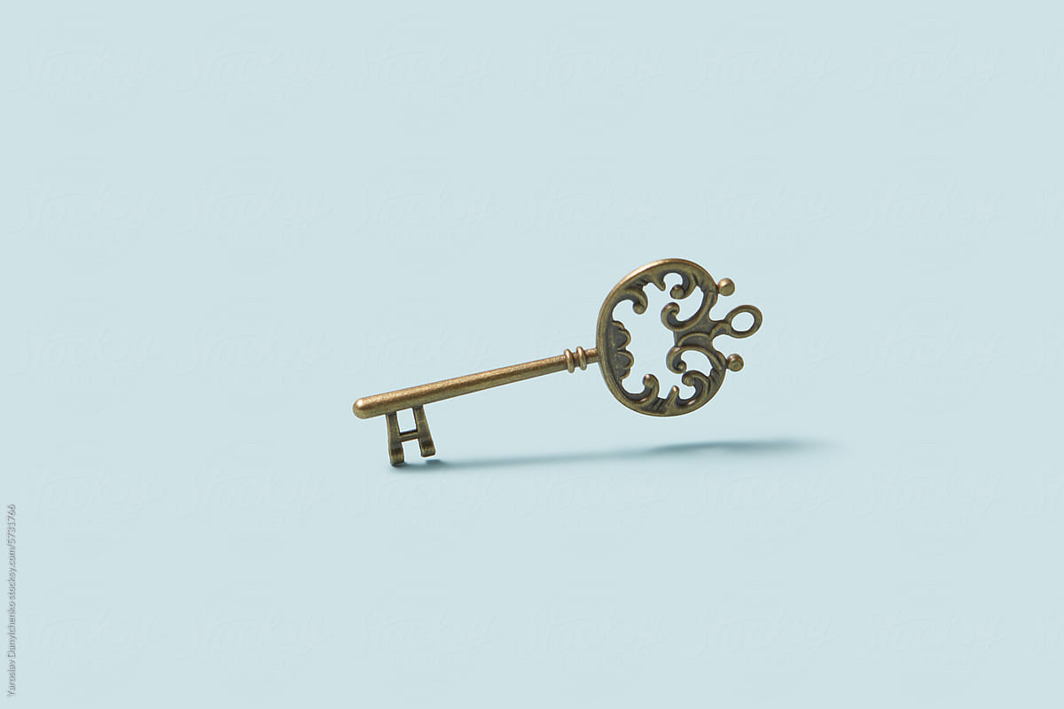 Old bronze key with levitating over light blue studio background