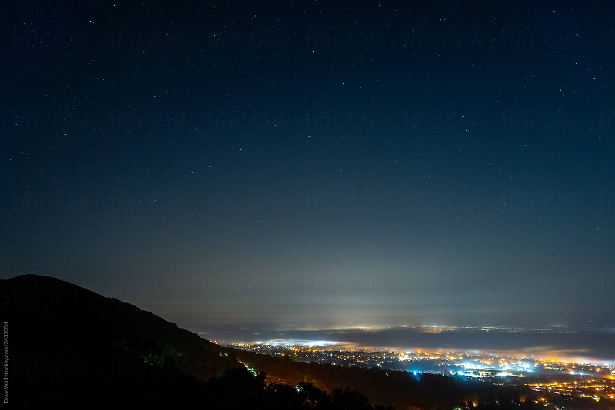 Looking down on a town at night, covered in fog.