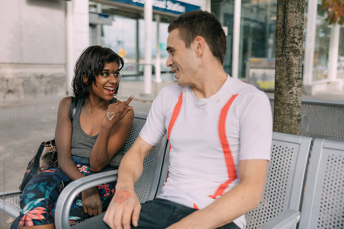 Couple together at transit station being silly and laughing.
