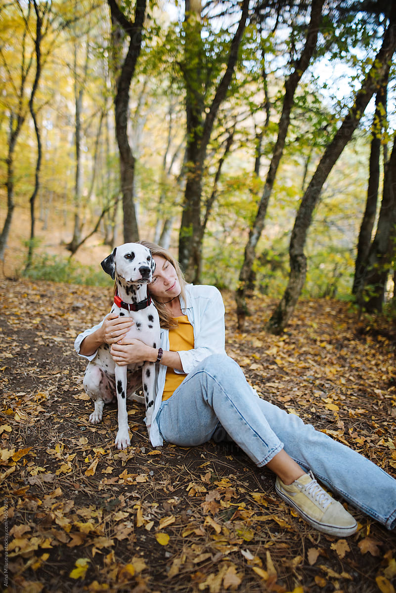 Peaceful woman hugging her dog in autumn forest