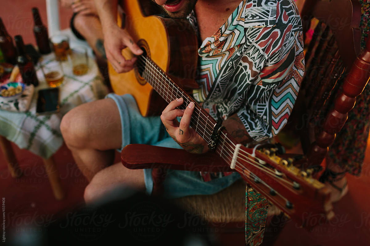 Close-up view of a young man playing the guitar