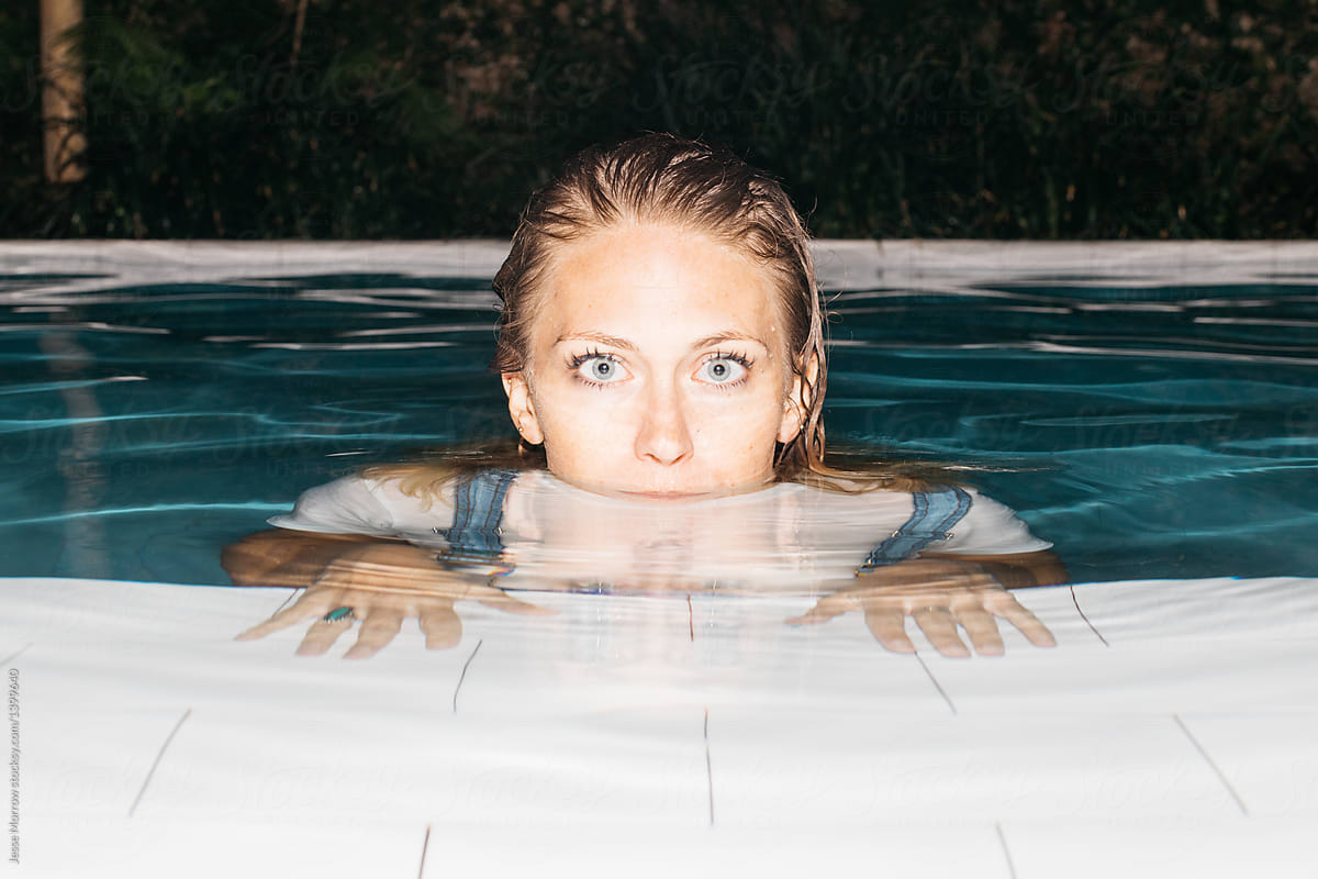 Portrait of young woman in pool water with bright blue eyes