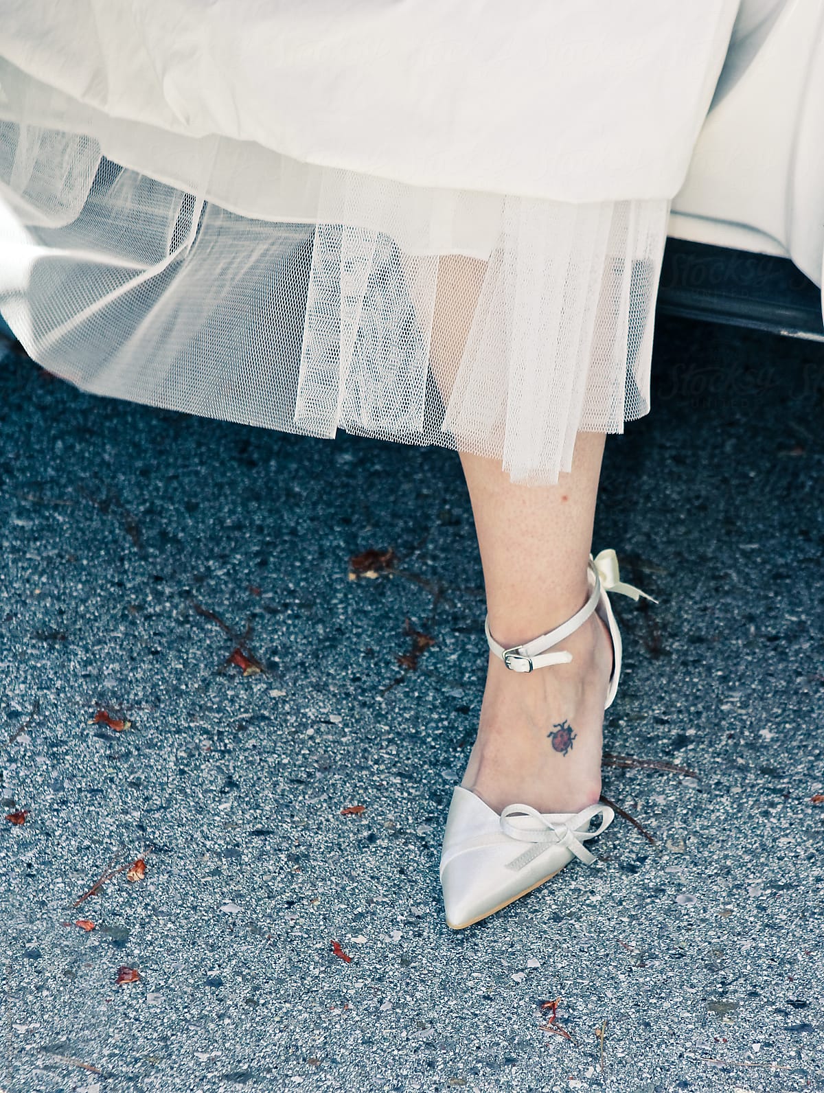 Bride stepping out of limo, focus on lower part of her dress and shoe