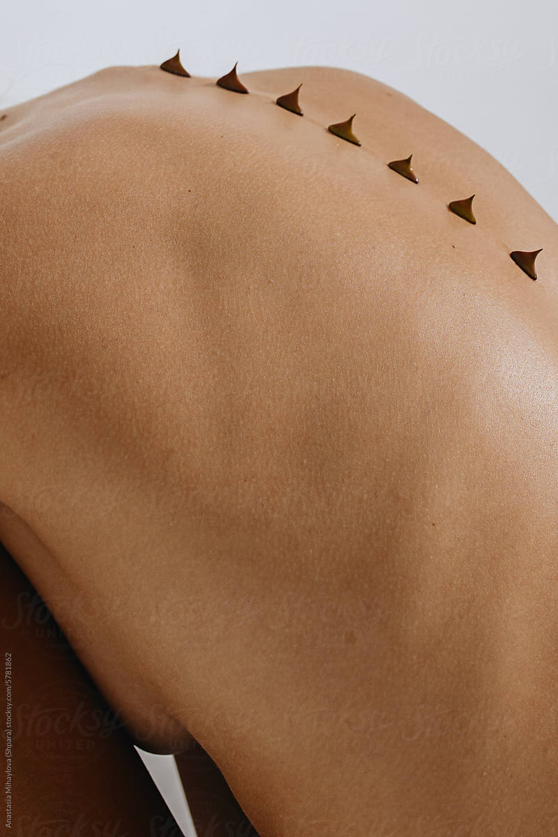 Close up photo of naked woman\'s skin of the back with thorns on spine