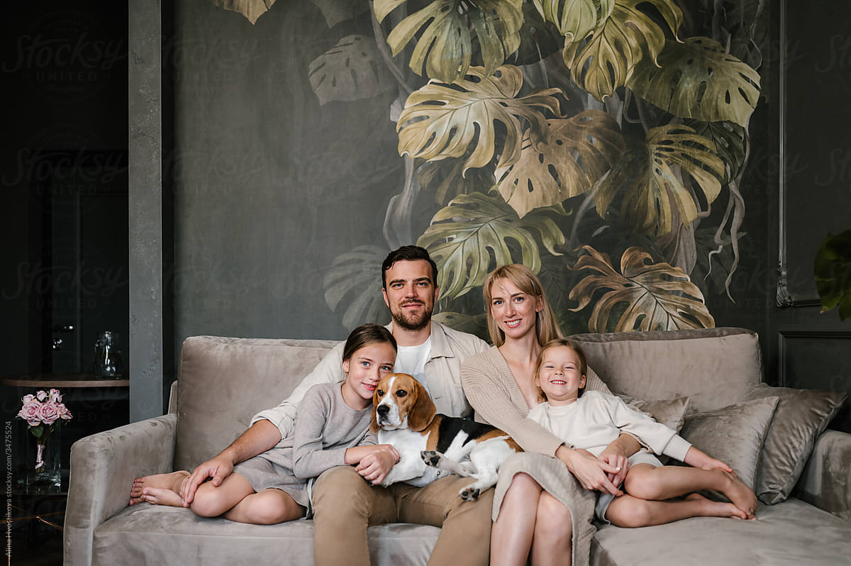 Happy family with dog resting on couch