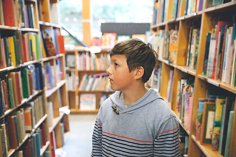 A young boy searches for books in a bookstore / library