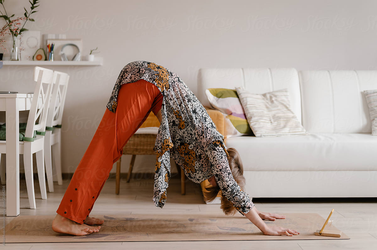 young-woman-doing-downward-facing-dog-exercise-at-home-by-stocksy