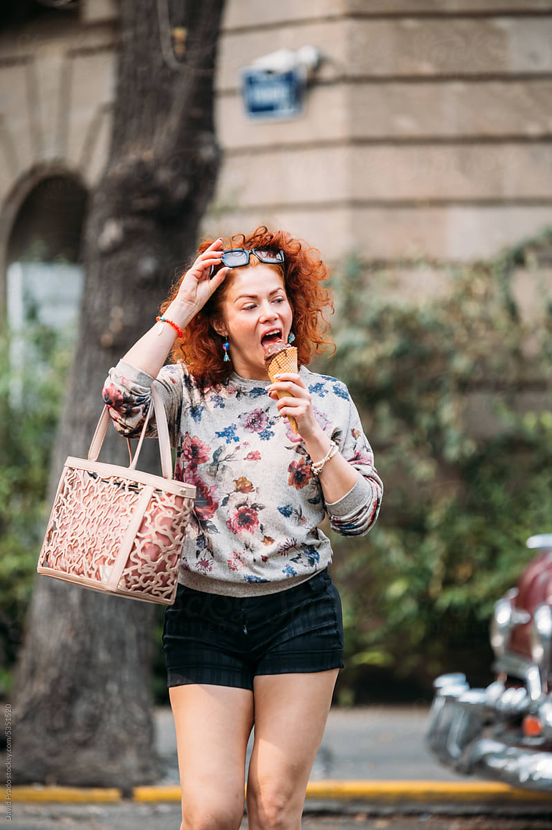 Cheerful woman with ice cream cone on city street