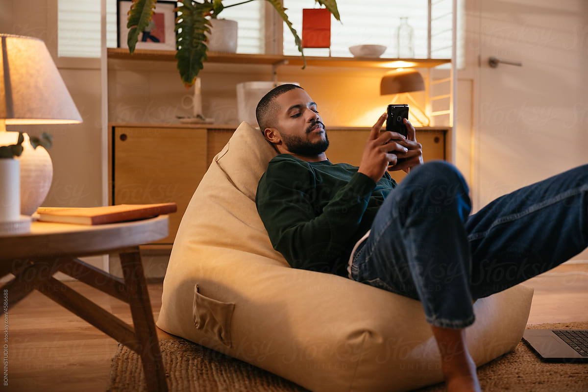 Man with smartphone resting on bean bag