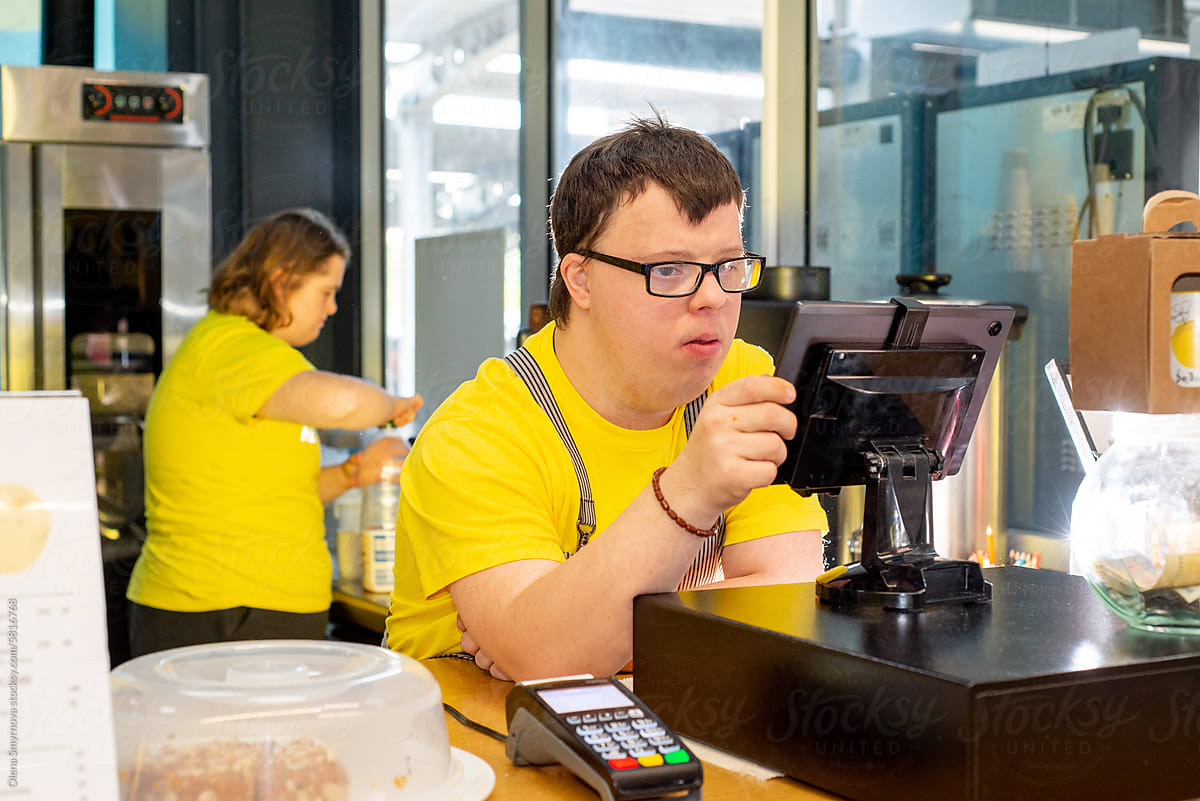 Young guy with Down syndrome works at the cash register