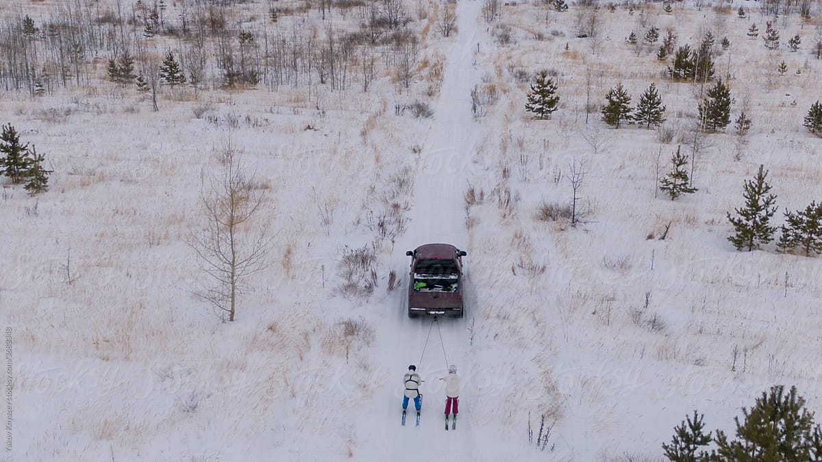 Winter fun: couple riding ski towed  to the car