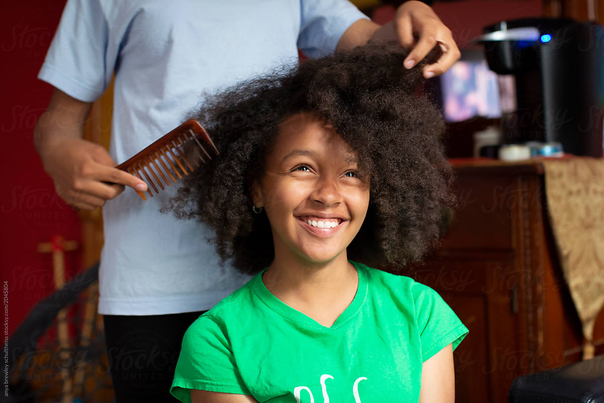Teen getting her curly hair combed