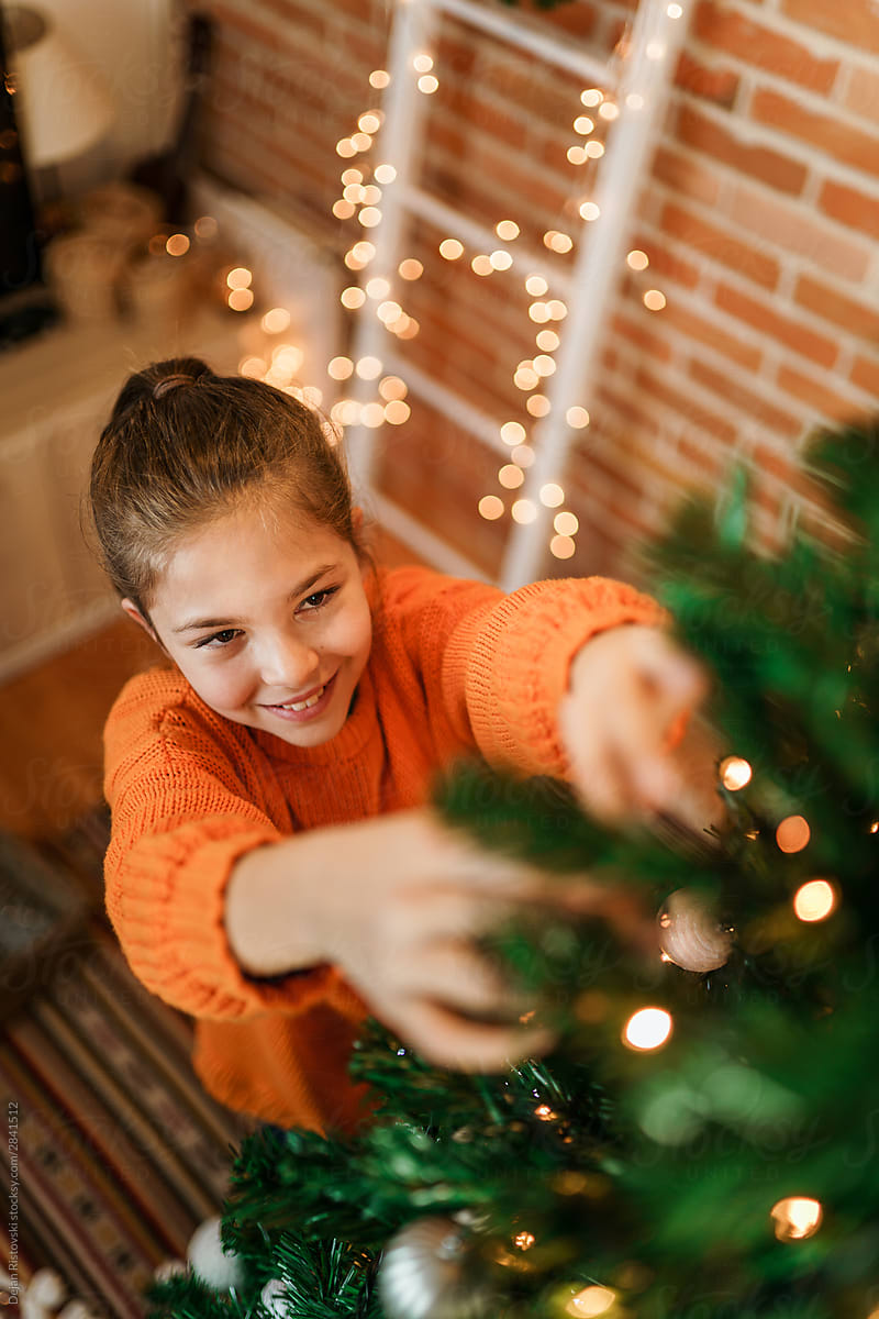 Teenage girl decorating Christmas tree by Dejan Ristovski - Stocksy United