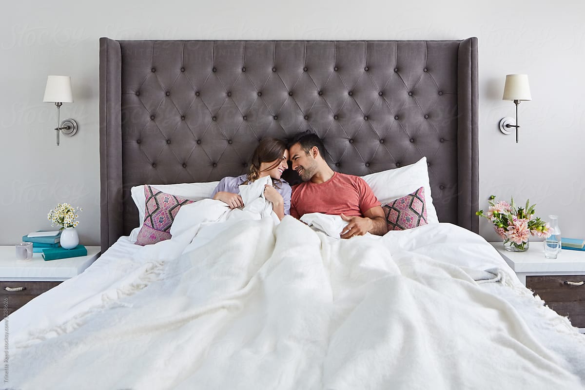 Young Multiethnic Couple Snuggling In Bed In The Morning By Stocksy Contributor Trinette Reed