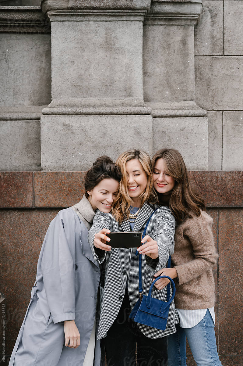 Cheerful girlfriends taking selfie on street