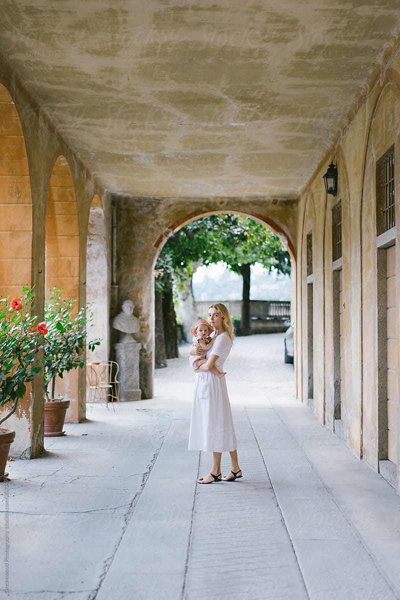 Woman standing with baby in arched walkway