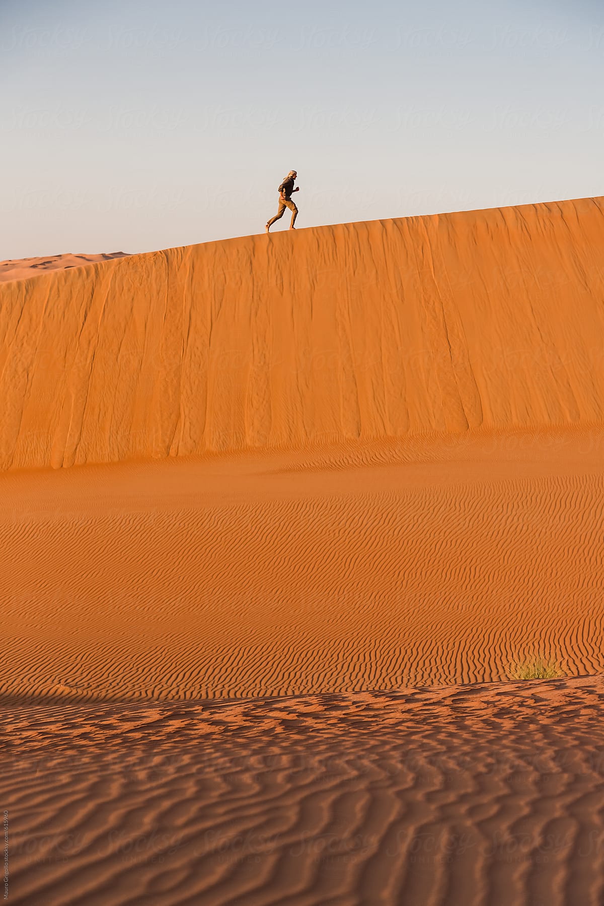 A man walks on a sand dune