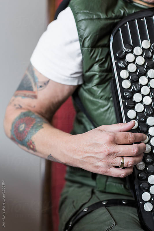 Closeup of a tattooed arm playing the accordion
