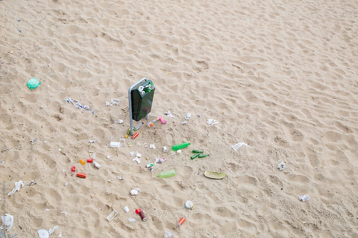 Pollution on beach, a rubbish bin full and overflowing onto the beach. Plastic Packaging
