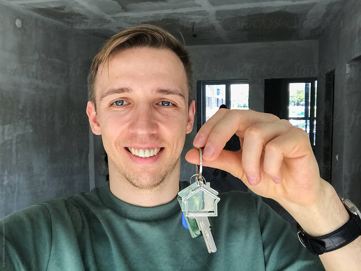 happy millennial man selfie holding key from a new home/apartment