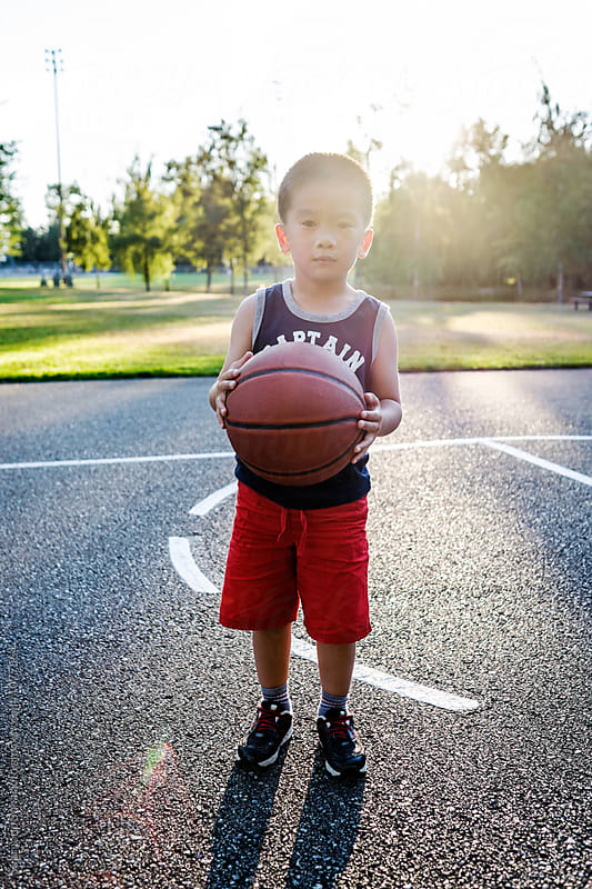 Asian kid holding a basketball in an outdoor basketball court