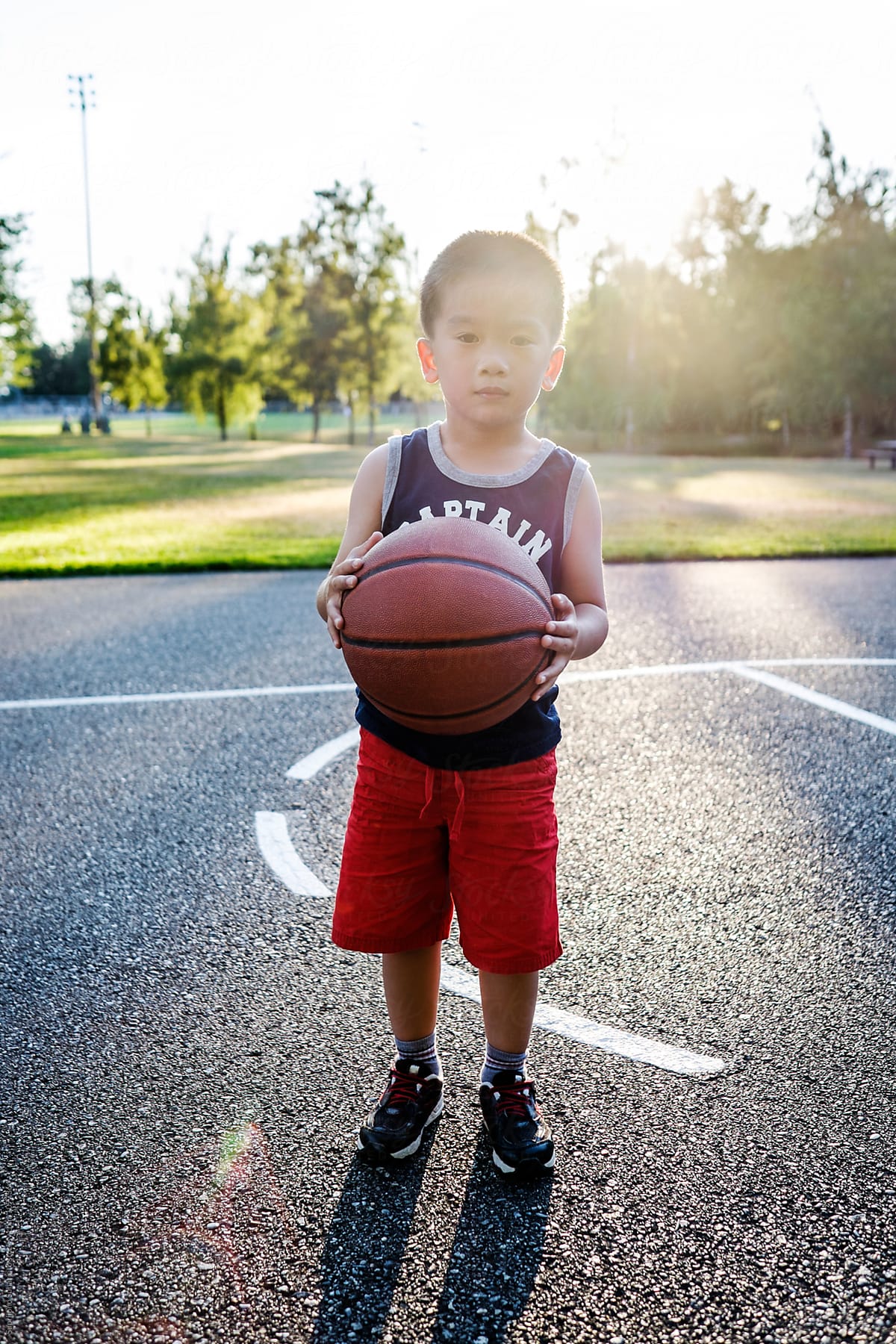 Asian kid holding a basketball in an outdoor basketball court