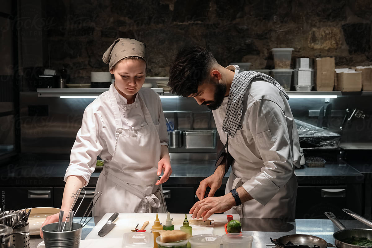 Man and woman cooking dish in restaurant kitchen
