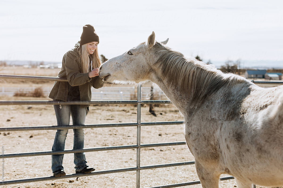 Smiling Woman Petting Horse in Pen