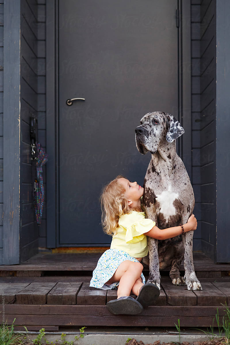Little owner hugging dog on porch
