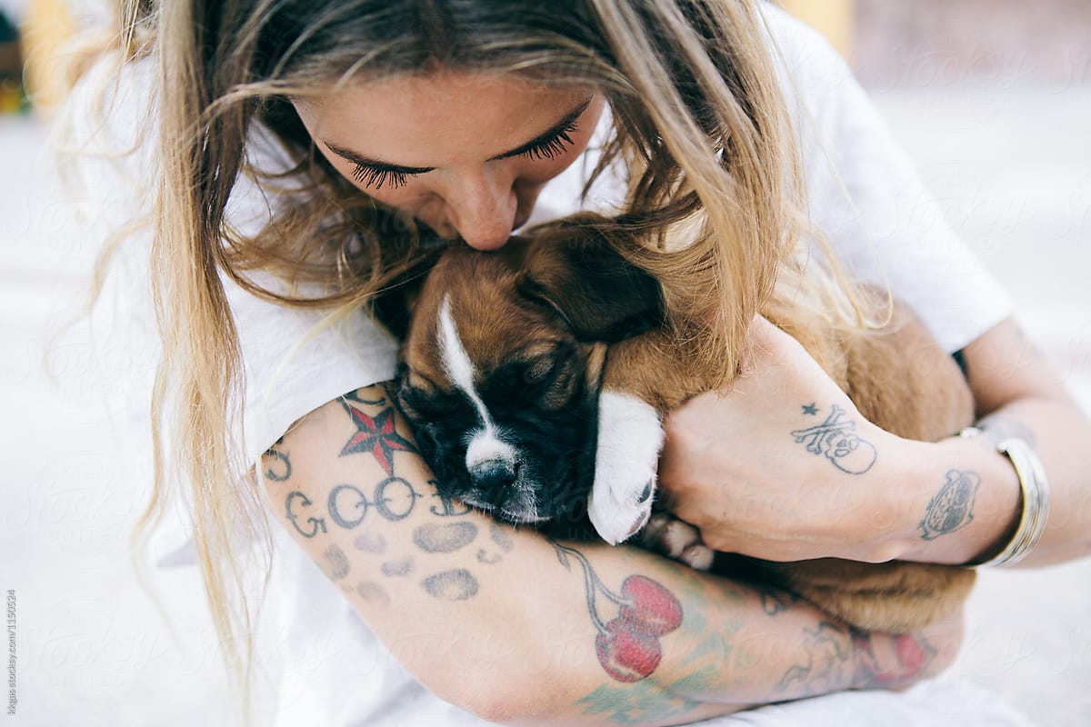 Beautiful tattooed woman cuddling a puppy