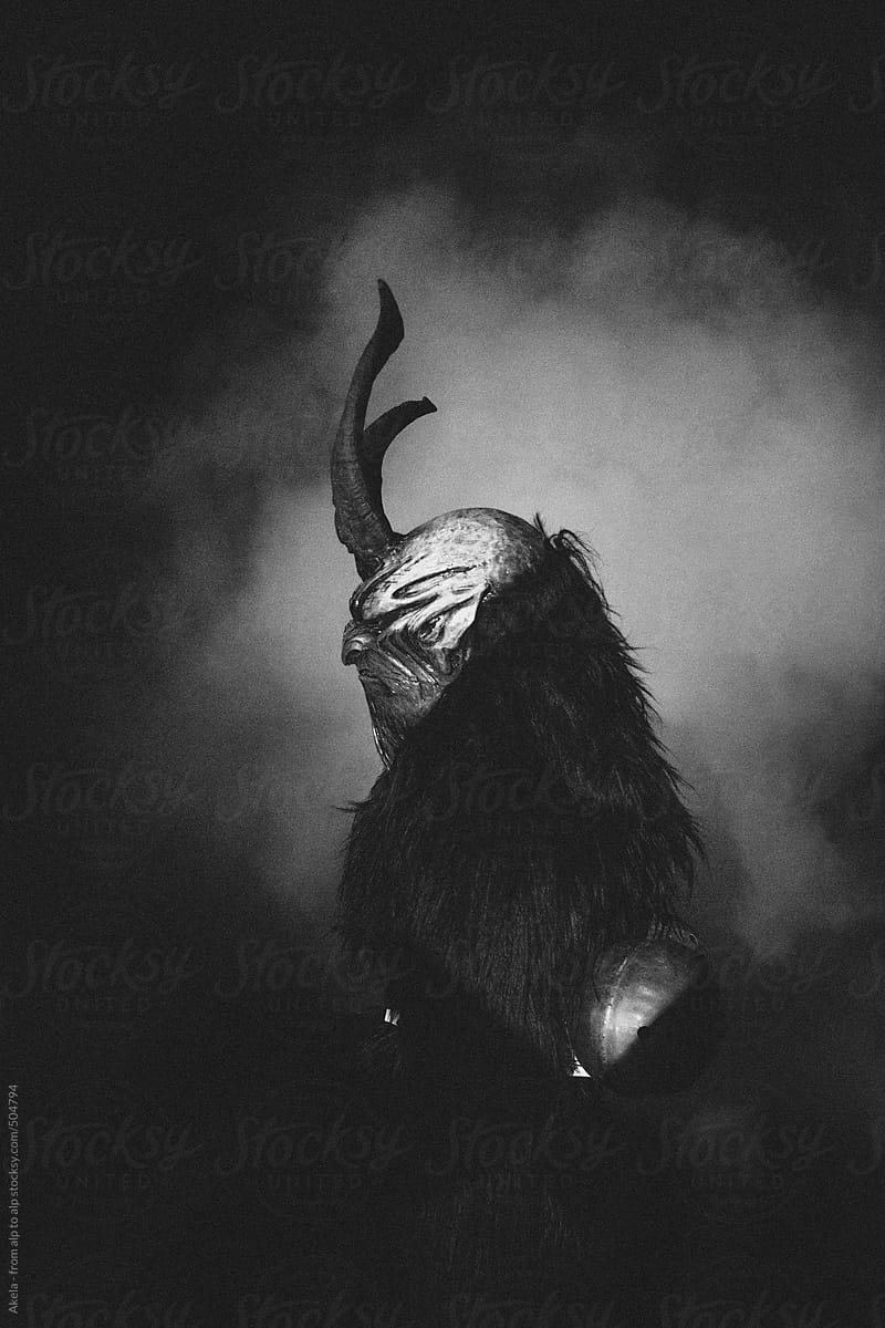 side view of a scary krampus with big bells and horns on his mask