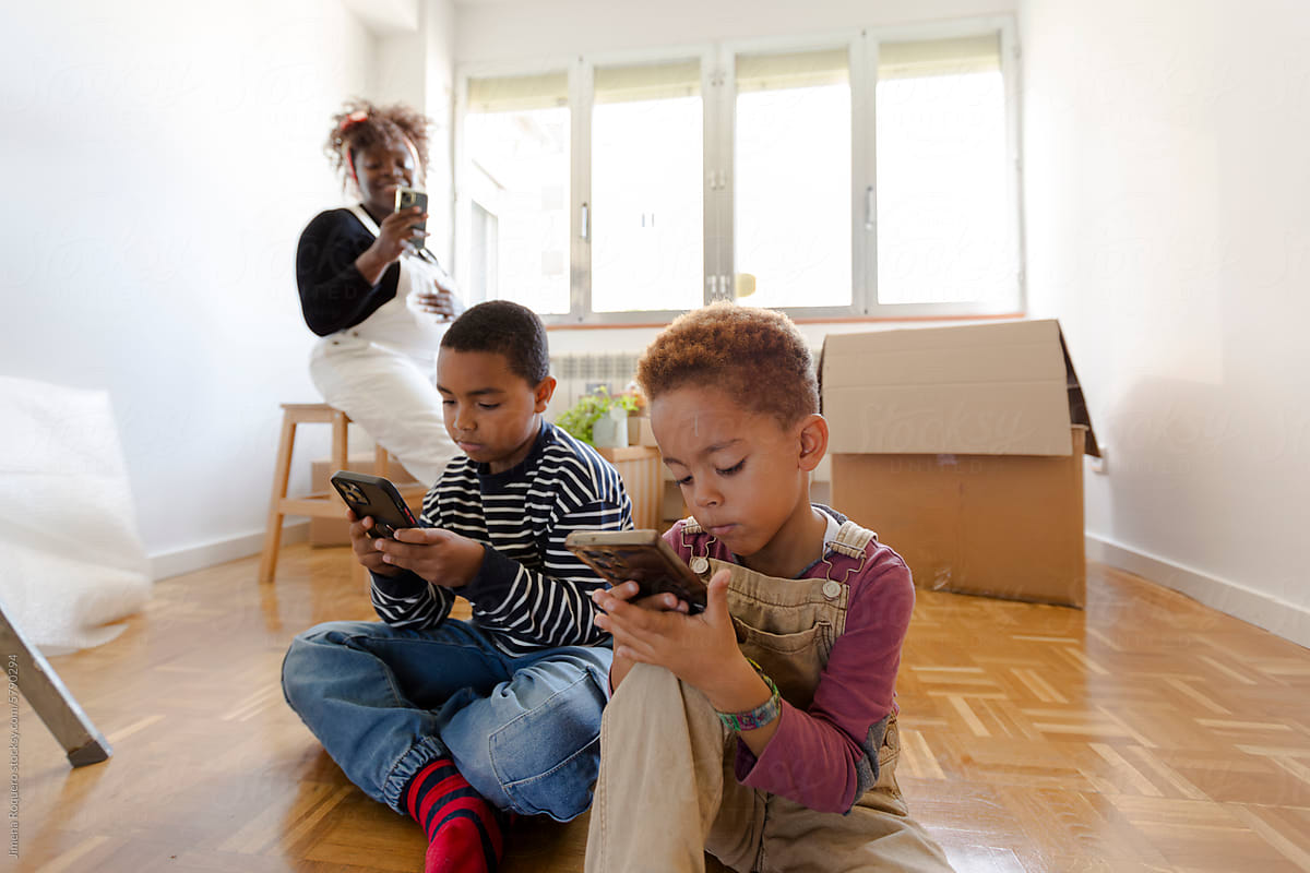 Kids playing with smartphone in new empty home