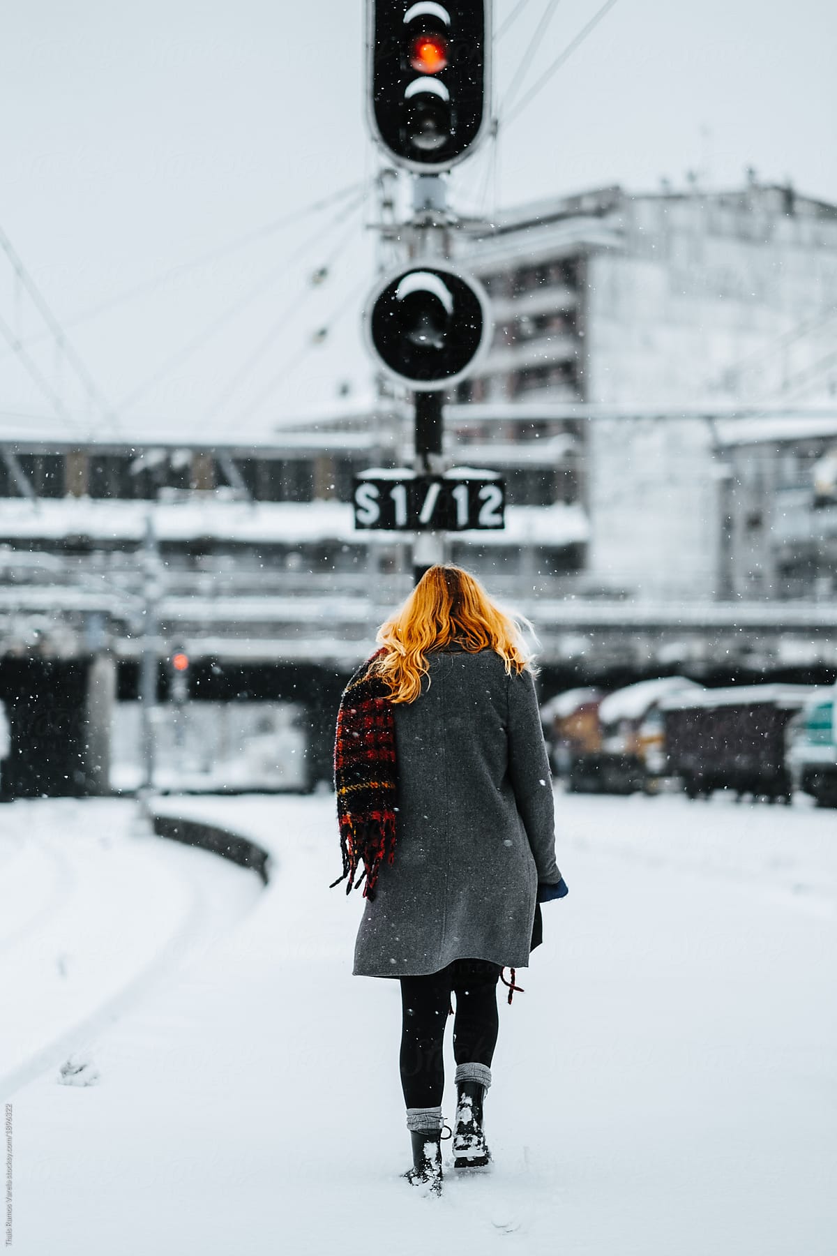 redhead woman walking on snowy train tracks