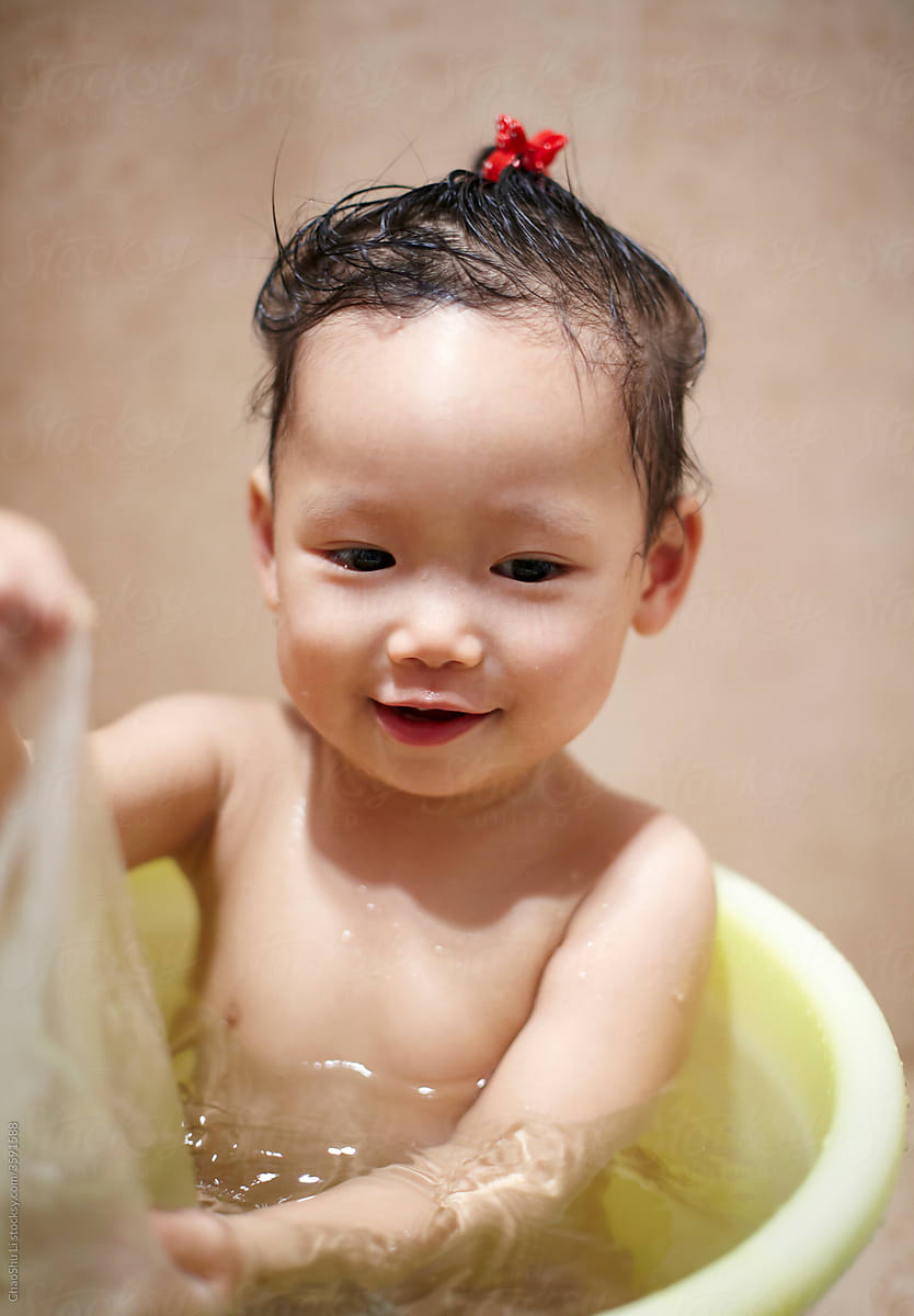 Cute Asian kid playing in the bath bucket in the bathroom
