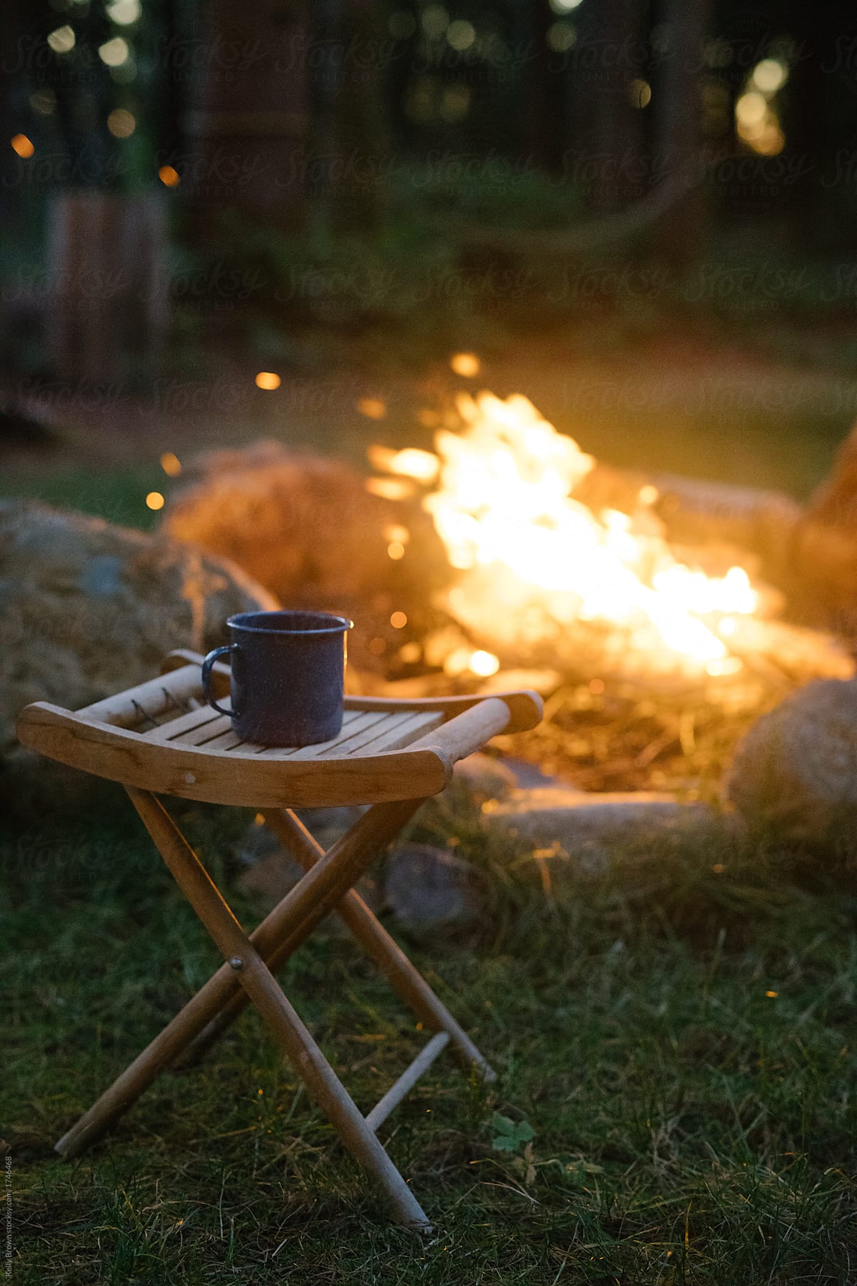 a campfire with an enamel cup on a wooden stool