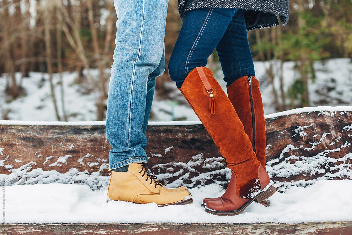Winter cold closeup of young couple in love standing in snow in their warm shoes