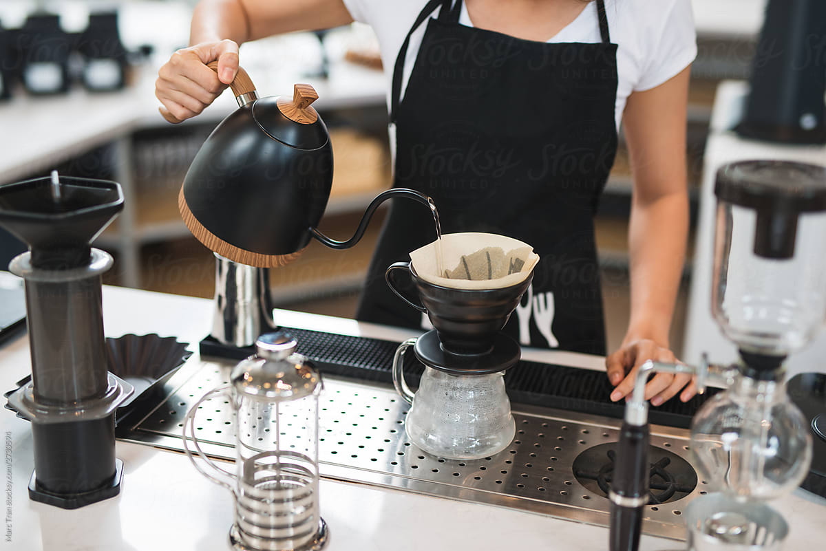 Young female barista preparing coffee in the morning