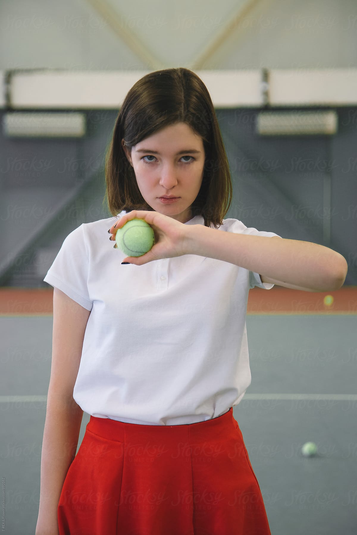 Girl Holding Tennis Ball In Front Of Her While Looking At Camera Del