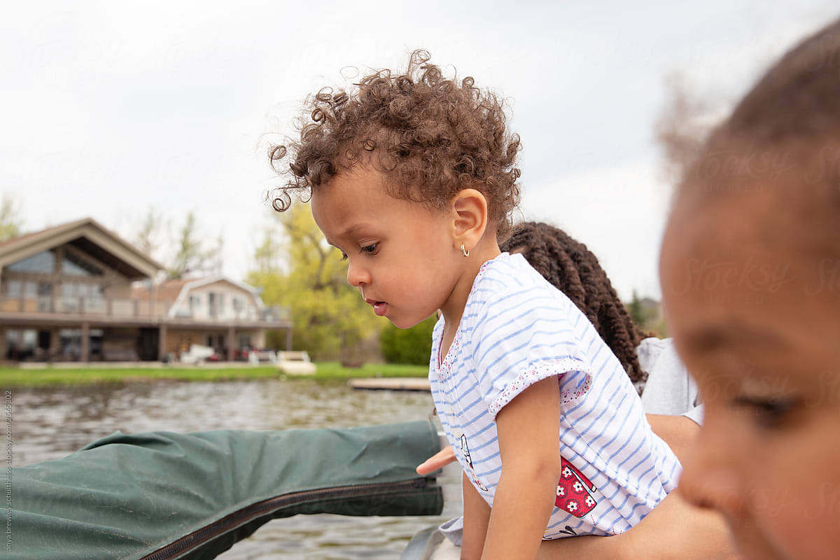 Curly haired toddler looking over the back of a boat